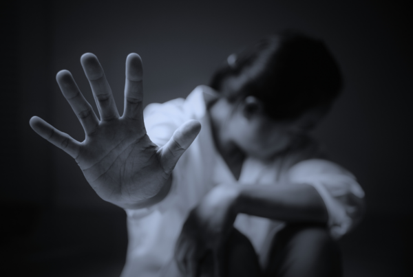 Personne détournant le visage, main tendue vers l’objectif en signe de refus, illustrant l’absence de consentement en cas d’agression sexuelle ou de viol