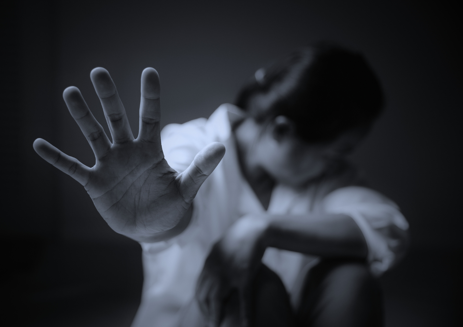 Personne détournant le visage, main tendue vers l’objectif en signe de refus, illustrant l’absence de consentement en cas d’agression sexuelle ou de viol